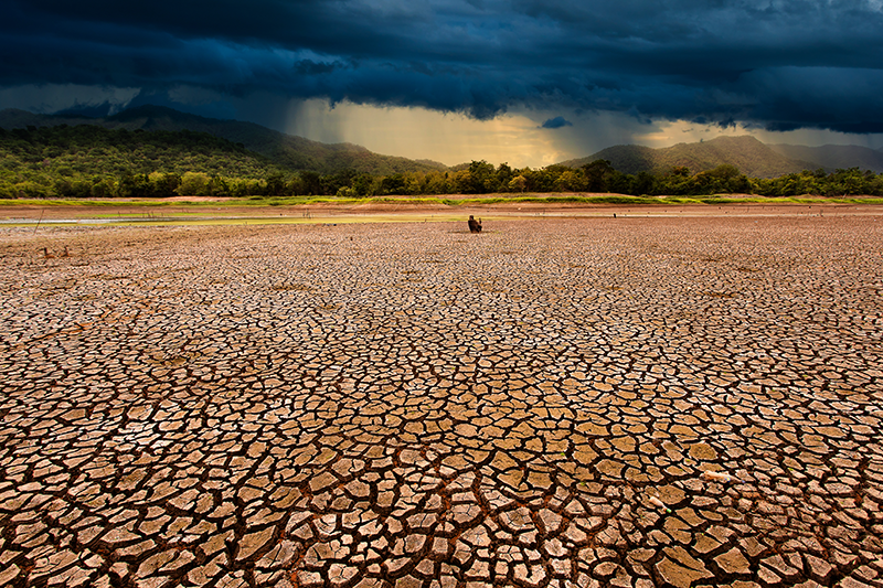 dry cracked earth with single figure in the background